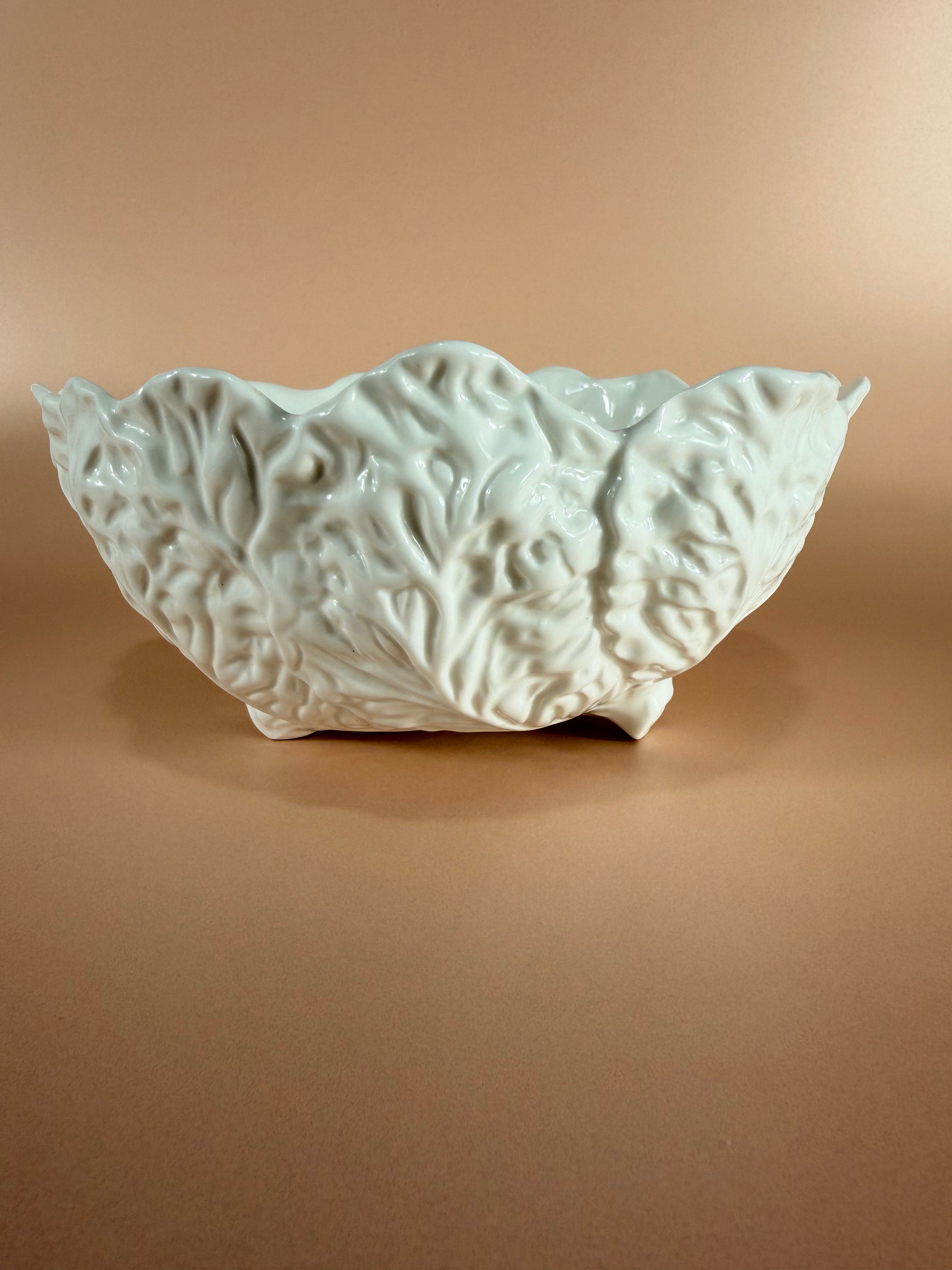 A white ceramic bowl with a textured, leaf-like raised pattern, set against a solid warm brown background.