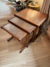 Set of wooden nesting tables with patterned tops on a wooden floor.