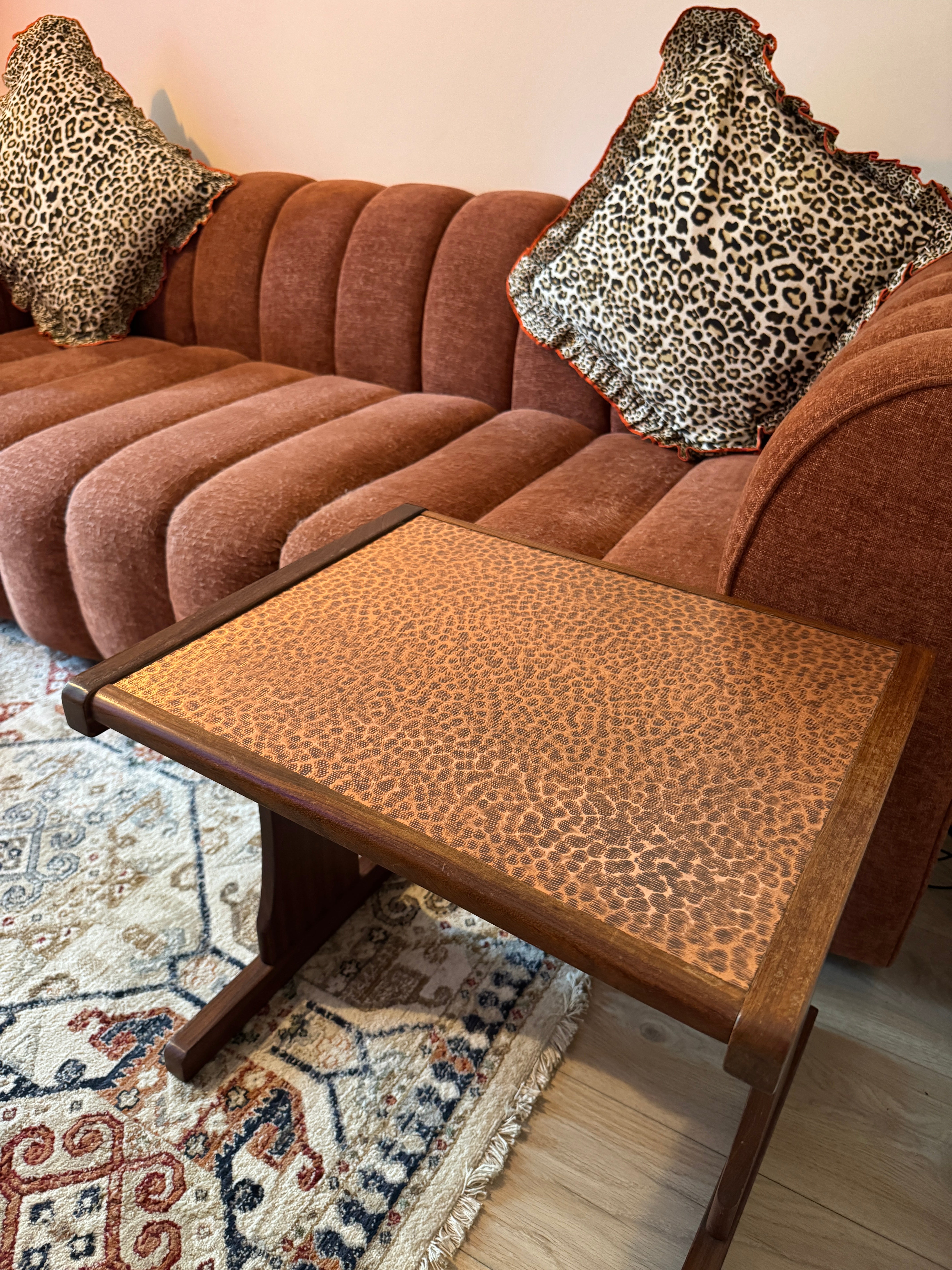 Brown sofa with leopard print pillows and a matching side table in a living room setting.