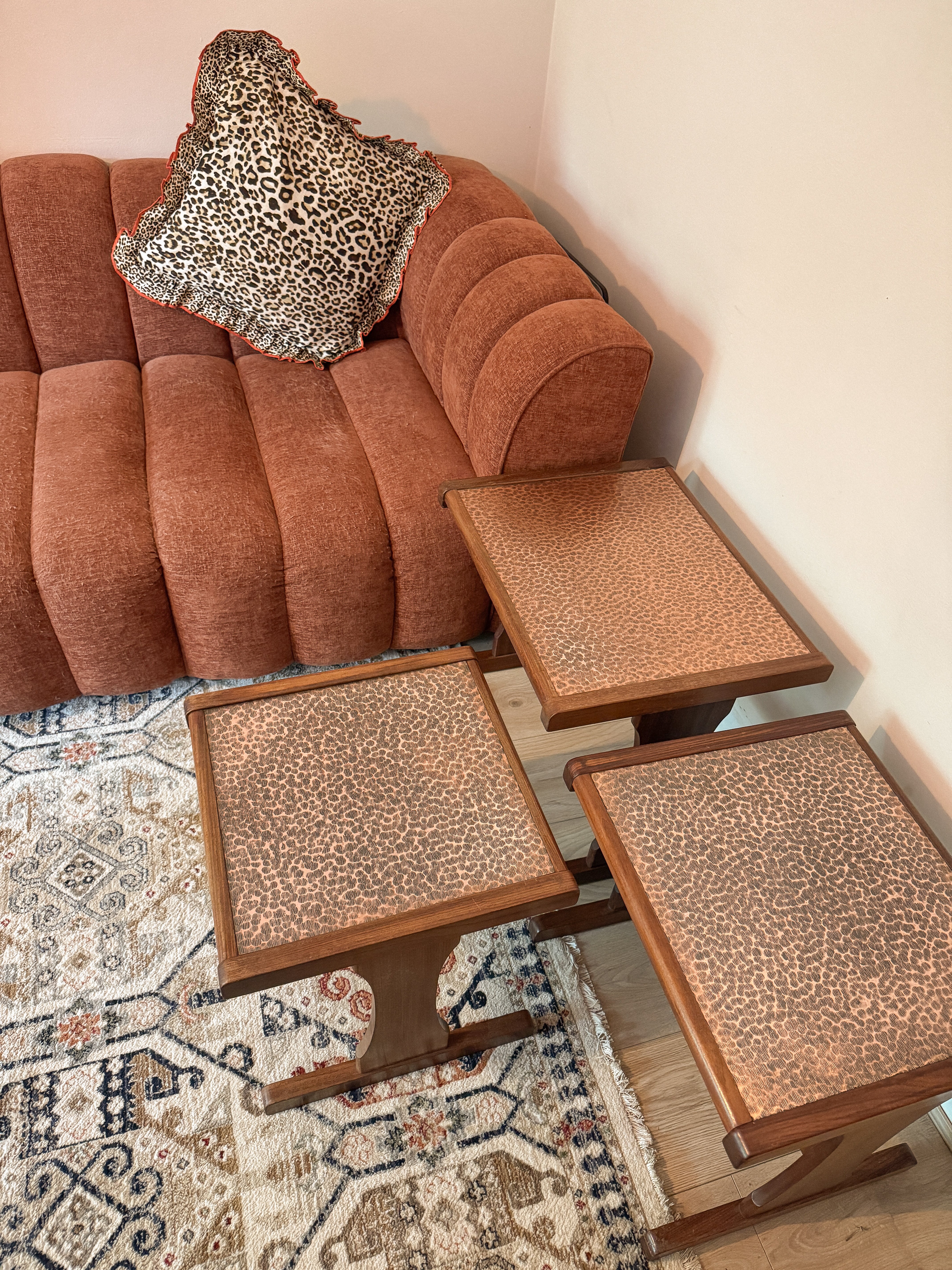 Brown sofa with leopard print blanket and matching ottomans on a patterned rug.