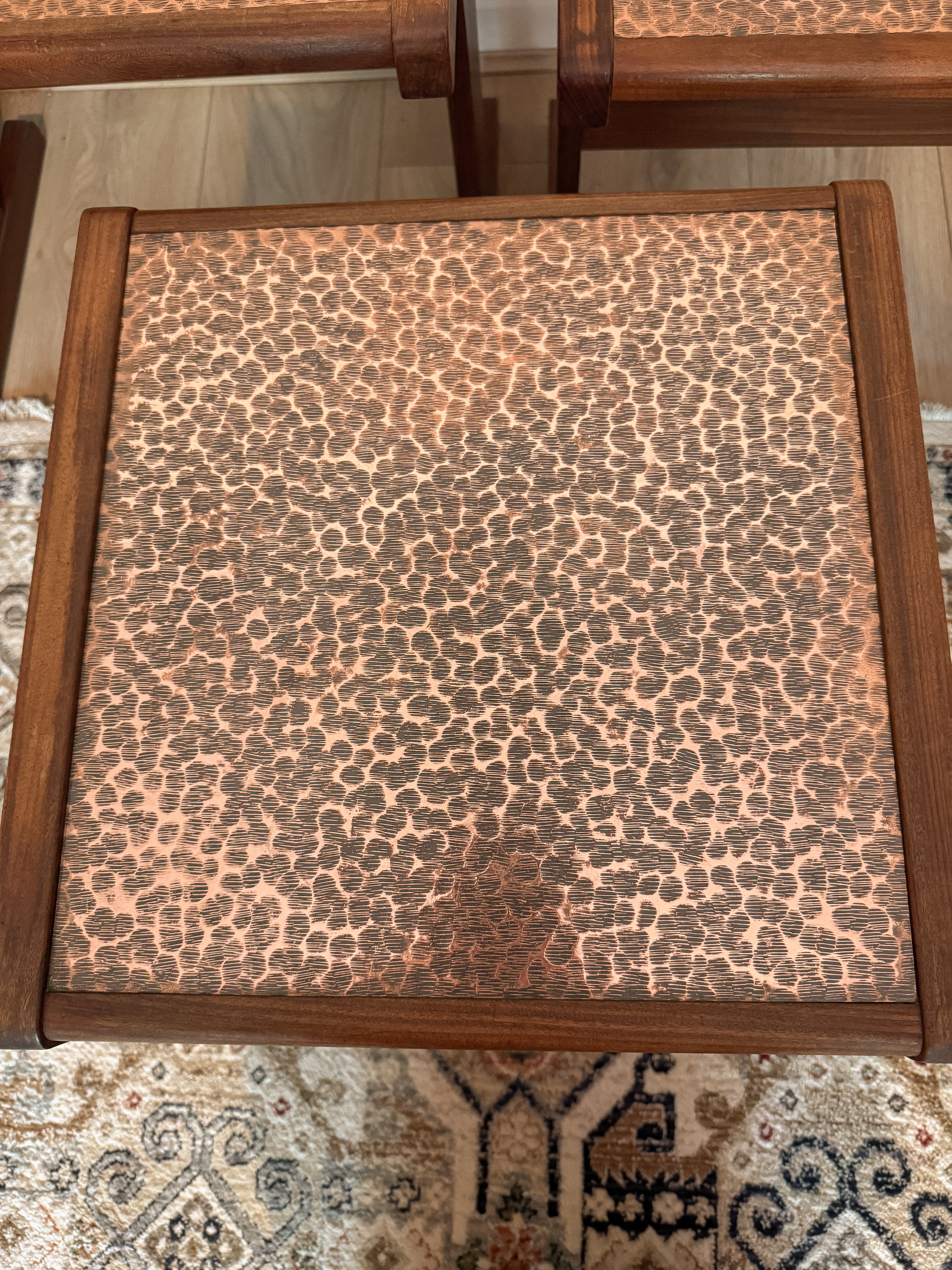 Wooden stool with a patterned fabric cover on a textured rug