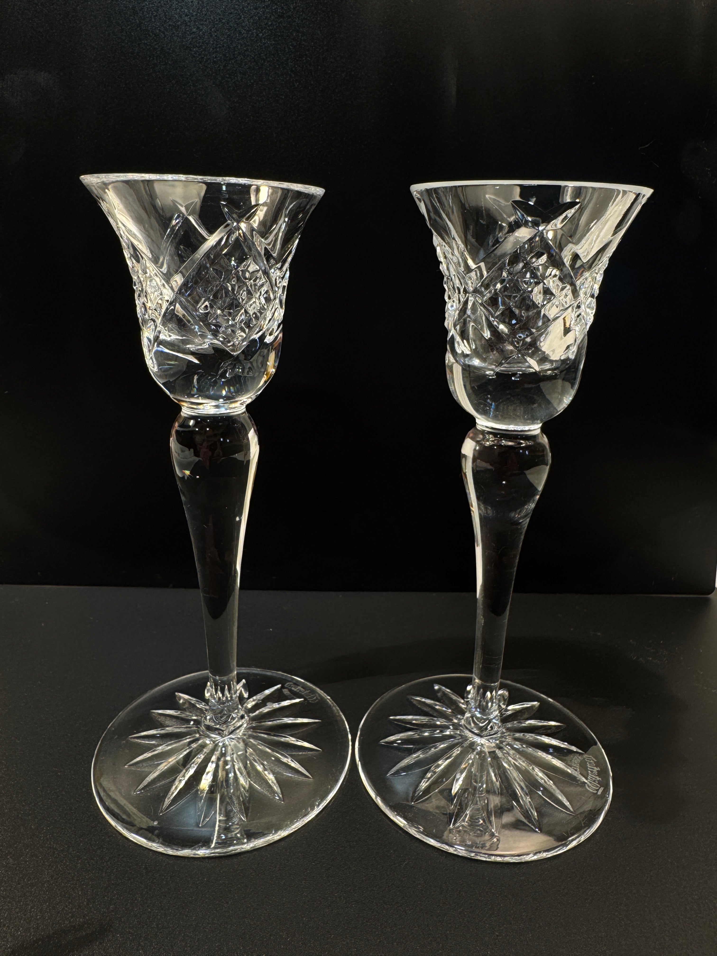 Two crystal wine glasses with intricate designs on a black background